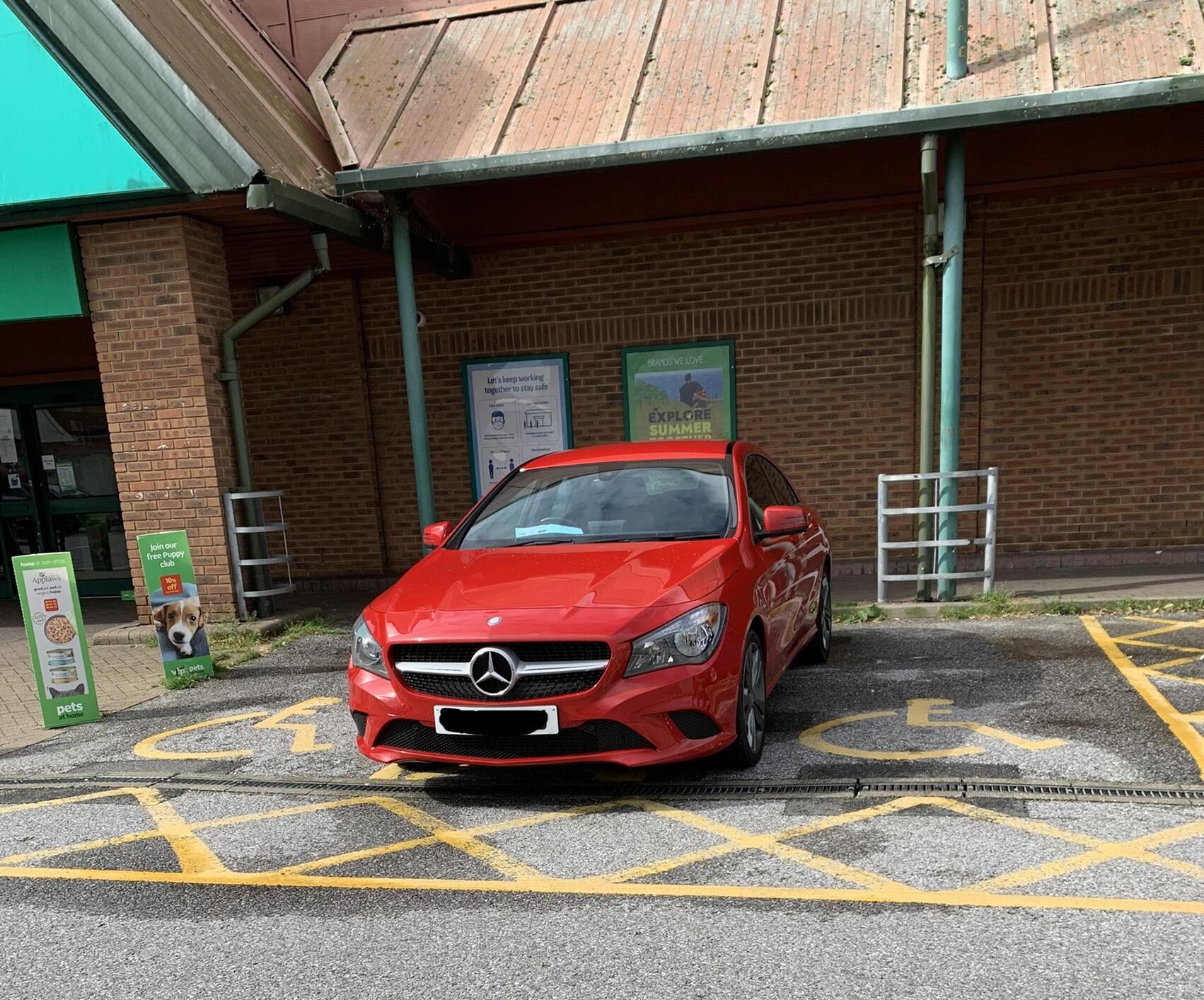 Red Merc parked over two disabled bays.